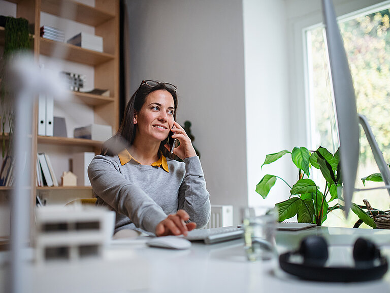 Frau telefoniert an ihrem Schreibtisch mit Avaya Telefon